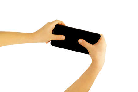 A child with two handles holds a smartphone, with thumbs presses the screen, isolated on a white...