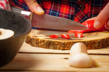Close-up knife cuts paprika on a round cutting board, on a wooden backgroundの写真素材