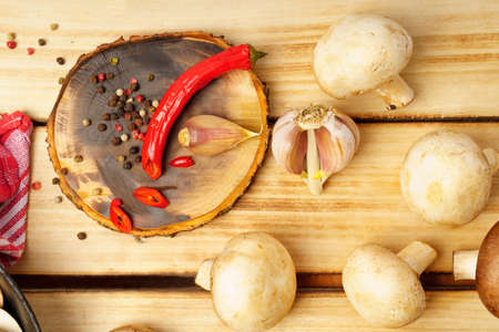 Sliced peppers, peppers, garlic on a round cutting board, champignons on a wooden background. Close-up, top viewの写真素材