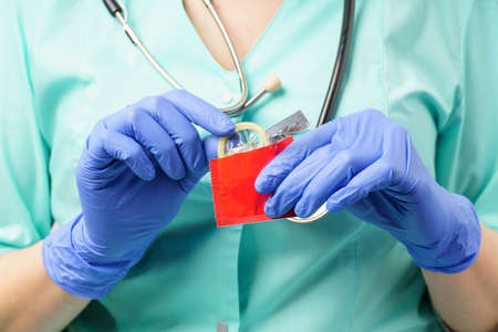 a doctor in medical gloves prints a condom. close-up