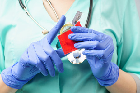Close-up of female hands in medical gloves open a condom. A woman doctor shows how to protect herself from sexually transmitted diseases.の写真素材