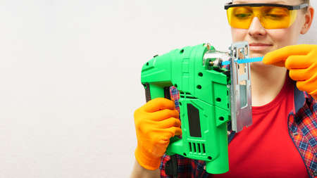 Carpenter inserts file into electric jigsaw on white background with copy spaceの写真素材