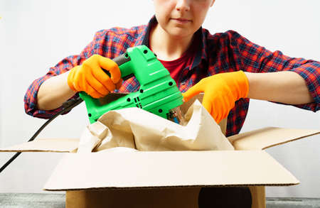 Unpacking a new instrument. A woman takes a jigsaw out of a paper box. new acquisitionの写真素材