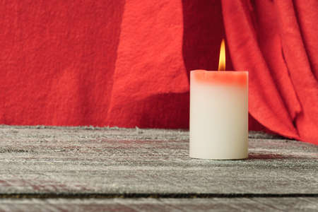 Lighted candle on a black table, in the back red backgroundの写真素材