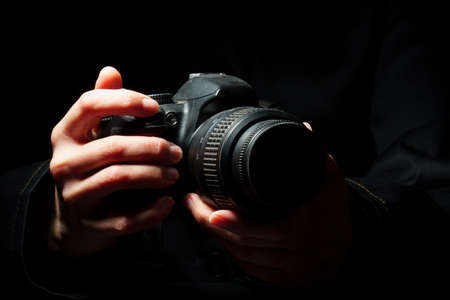 close-up of a camera in female hands on a dark background.の写真素材