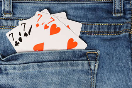 playing cards in jeans pocket. four sevens on blue jeans. gambling addiction conceptの写真素材