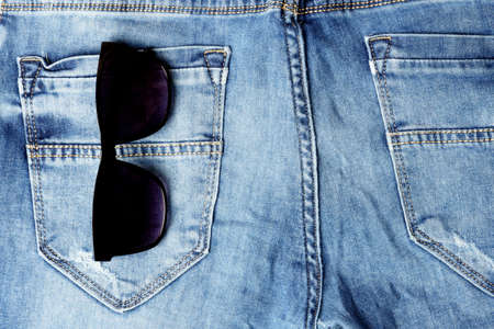 Black sunglasses in the pocket of blue jeans. Close-upの写真素材