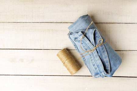 blue jeans rewound with thin scourge on white wooden table, with copy spaceの写真素材