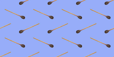 Pattern from wooden spoons on a blue background. Seamless background from wooden spoons. Wooden cutlery.の写真素材