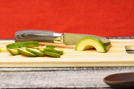 Avocado slices and knife on a wooden board. making avocado salad.