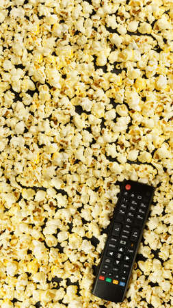 Black TV remote control, background with popcorn. Leisure concept. Flat lay, top view
