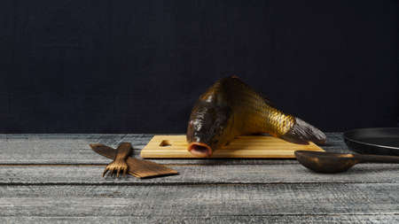 Freshwater fresh raw carp on a cutting board, on a black table, copy space. Baner