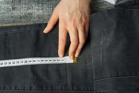seamstress measures jeans with a measuring tape. white meter on jeans, close-upの写真素材