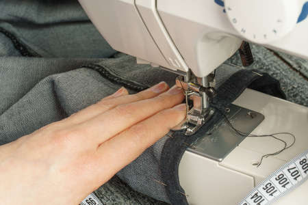 the process of shortening jeans pants on a sewing machineの写真素材