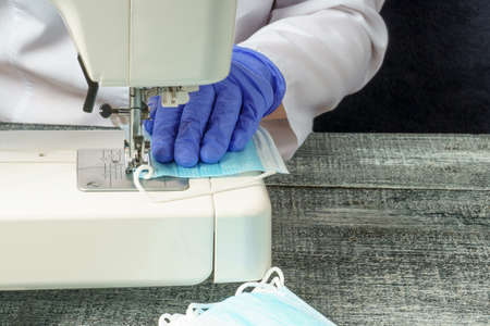 A woman's hands sew a medical face mask on a sewing machine during the pandemic.