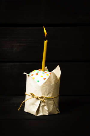 Easter cake on a dark background, with a burning church candle,