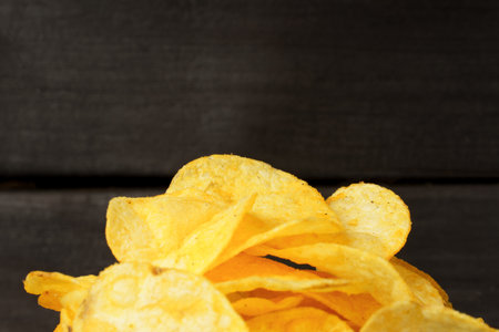 close-up of a bunch of potato chips on a dark wood backgroundの写真素材