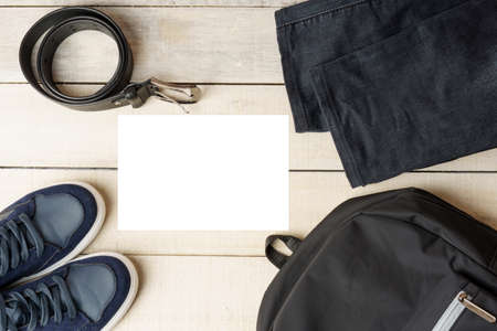 Set of men's clothing and accessories on a white wooden background. Backpack, sneakers, belt, and...