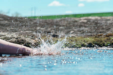 splash hands in a puddle. a female hand clapping in a puddle.