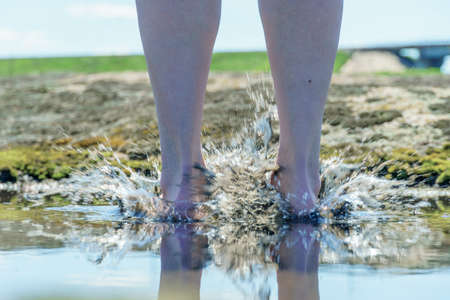 barefoot in a puddle. woman walks barefoot in a puddle outdoors. close-up