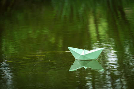 origami paper boat floats on the river. children's summer entertainment. toy paper