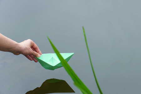 paper boat in a female hand. origami paper boat floats in the river. paper toy