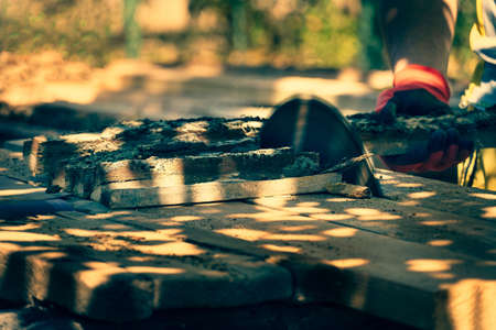 a carpenter works behind a circular saw. a man cuts a wooden board at a sawmill on a sunny day,...