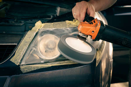 cleaning headlights with a buffer machine. the master polishes the headlights of the car.