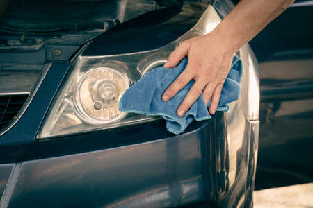 headlight cleaning. A man wipes the headlights of a car with a soft clothの写真素材