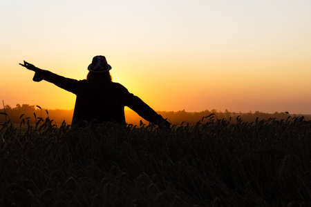 silhouette of a girl against the setting sun. young woman in a wheat field in the evening