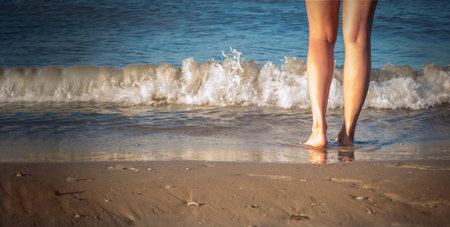 female legs on the seashore. body part, perfect tan of female legs, enjoying time on the beachの写真素材