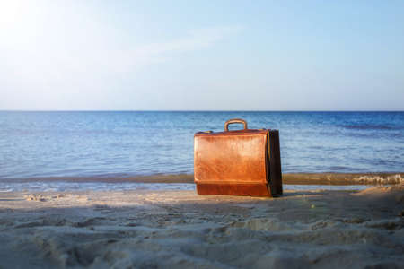 old brown suitcase on the seashore. vintage suitcase on the beach in the sunshineの写真素材