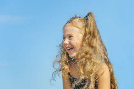 joyful child against the blue sky. little girl about 5 years old, laughing.の写真素材