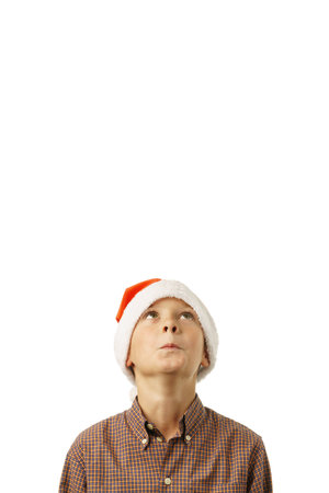 isolated on white background boy in santa hat looks up in surprise. Christmas card, banner. free placeの写真素材