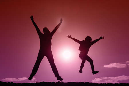 jumping child and girl at sunset. silhouette of happy people. photo in trendy colors of the yearの写真素材