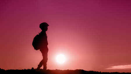 child at sunset. silhouette of a boy with a backpack, travel concept. photo in trendy colors of the yearの写真素材