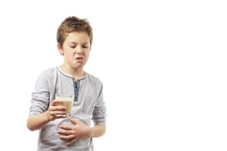 disgruntled child with a glass of milk isolated on white background.の写真素材