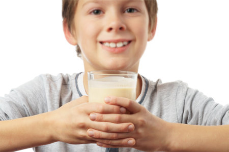 portrait of a happy caucasian boy with a glass of milk, isolated on white background. advertising concept.の写真素材