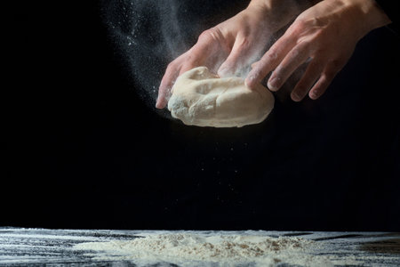 hands prepare the dough on a dark background. homemade dough
