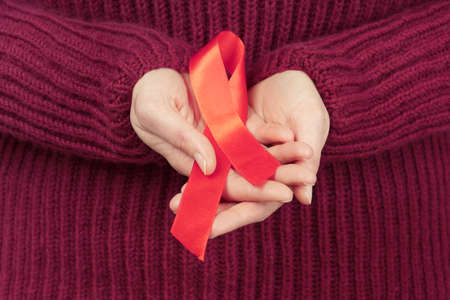 female hands holding red ribbon HIV awareness concept, world AIDS day, world hypertension day, world...