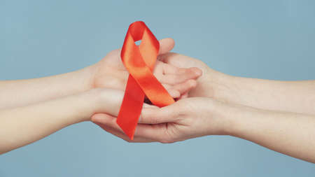woman and child holding red AIDS awareness ribbon, on blue background