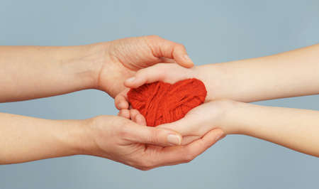 female and children's hands hold a heart on a blue background. family conceptの写真素材