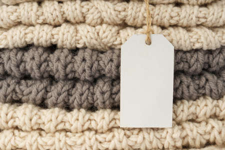 blank clothes tag, label mockup template on pile of knitted clothes closeupの写真素材