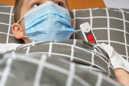 sick child in bed in a mask with a gadnikの写真素材