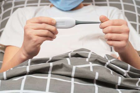 child looks at the thermometer. close-up of a childs hands holding a thermometer