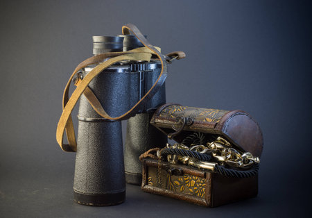 Old vintage Binoculars with treasure. Black background. Close up.