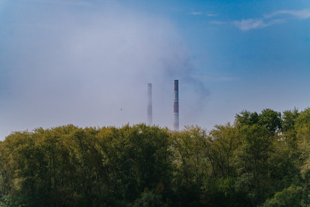 Green Village Near Factory with Tall Emitting Chimneys on a Summer Dayの写真素材