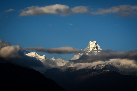 Mount Fishtail (Machapuchare) peeping through dark clouds in the morning hour, viewed from Tadapani, Nepalの写真素材