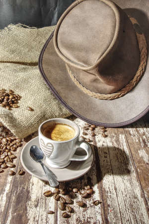 cup of espresso with coffee beans and leather hat on tableの写真素材