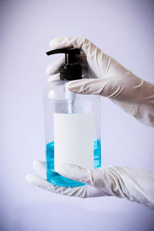 Presenting sanitizer bottle by both hands with medical latex gloves